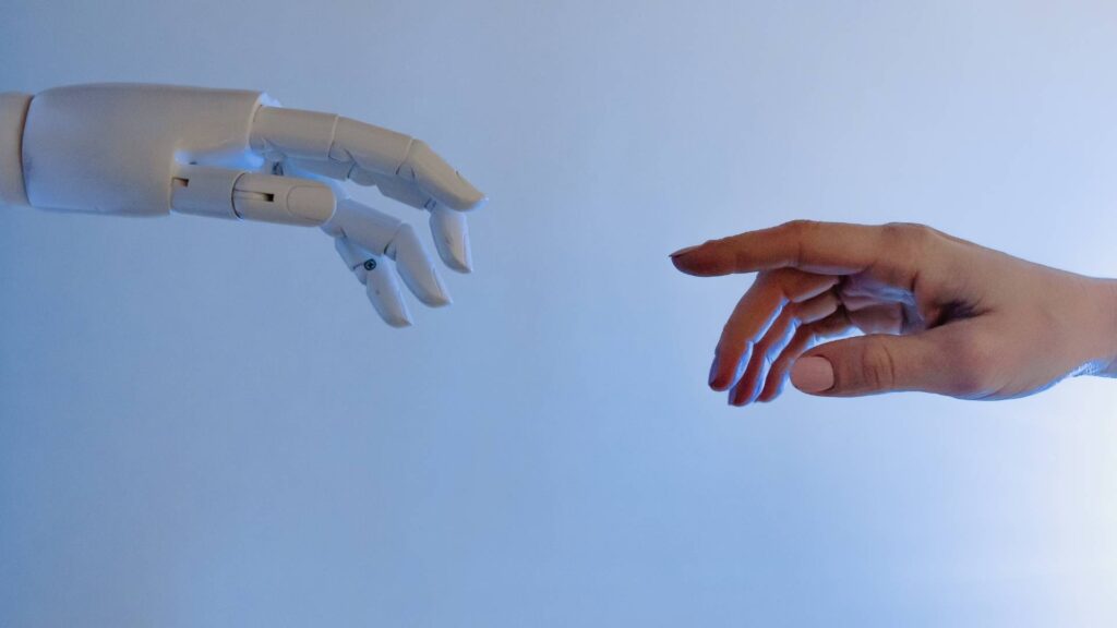 A robotic hand reaching toward a human hand, symbolizing the intersection of artificial intelligence and human content creation—representing how LLMs interpret and structure content for AI-powered search.